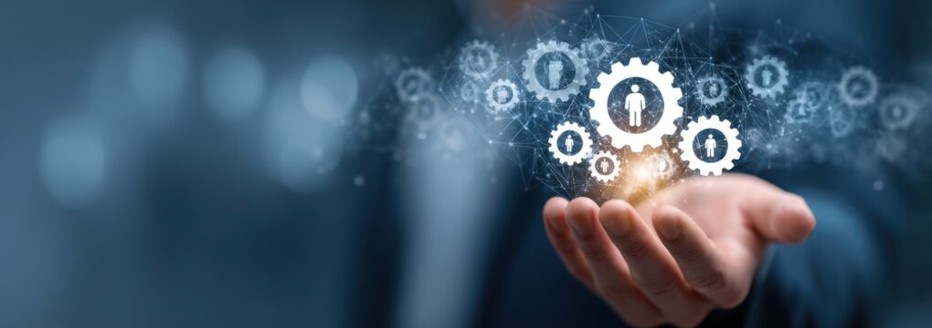 Hand holding glowing digital gears with human icons against dark background.