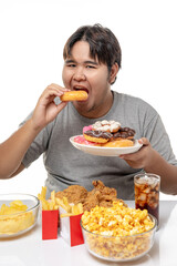 Overweight young man happy while eating a tasty donuts and hamburger and fried chicken, unhealthy junk food, studio shot.