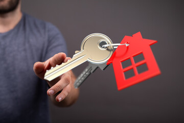 Person extending hand with home keys, symbolizing buying, renting, or owning a property.  Perfect for real estate, mortgage, and housing concept