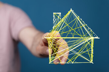 A conceptual image of a hand holding a digital house model connected by lines. This illustrates concepts of home ownership, real estate, and dig