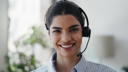 Video of smart business woman talking with earphones while doing a video call looking at camera in the office. - Powered by Adobe