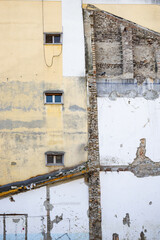 A partially destroyed wall reveals old bricks and textures showing the decay and history of an abandoned urban building.