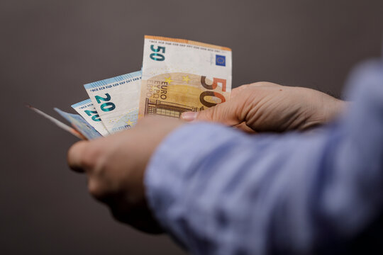 Person's hands holding and counting various euro banknotes. The image showcases money, wealth and financial concepts. Perfect for illustrating f - Powered by Adobe