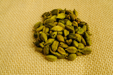 Whole cardamom pods aggregated, revealing natural green color and wrinkled surface texture.