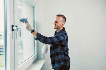 Man cleaning large window with smile, bright room filled with natural light, showcasing modern interior design in a cheerful atmosphere