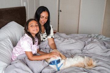 A woman and a girl are laying on a bed with a dog