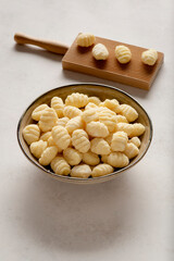 A bowl filled with raw gnocchi placed against a light background.