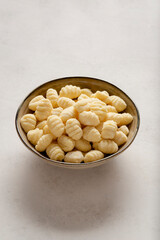 A bowl filled with raw gnocchi placed against a light background