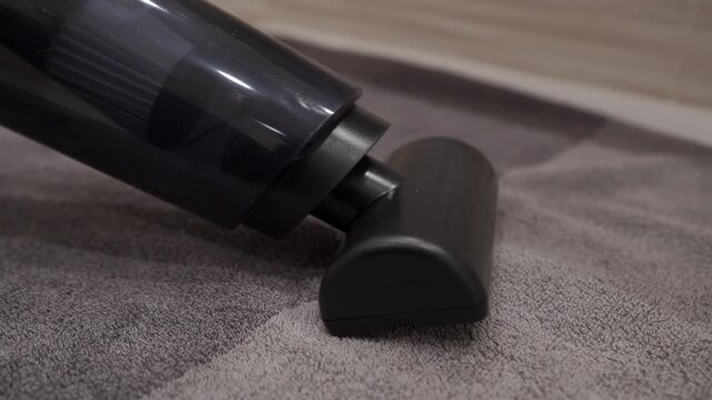 The plastic handheld car vacuum cleaner is operating. The motor is running to suck up dirt, creating a loud, continuous whooshing sound.