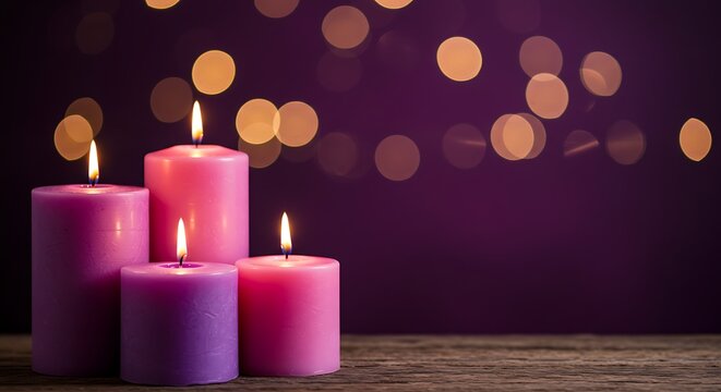 Four lit candles in shades of pink and purple with bokeh lights in the background