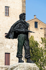 Bronze statue depicts heroic soldier with weapon standing proudly symbolizing courage freedom and sacrifice in front of historical buildings