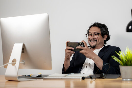 A young male office employee relaxing and playing games on his smartphone during a work break in the office.
