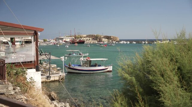 View of taverna with Limenas Chersonisou Port in background on a sunny day, Limenas Chersonisou, Crete, Greek Islands, Greece, Europe