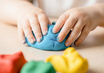 Childs hands sculpting with colorful modeling clay on a wooden table creative fine motor skills development activity