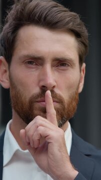 Portrait Caucasian business man showing silence gesture hush sign mature businessman in city male worker entrepreneur holding finger mear mouth forbid talking secret confidential information symbol