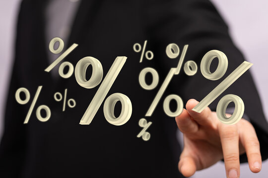 A businessperson's hand interacts with floating percentage signs. Illustrating finance, investment, market, and economic growth and success. Sui - Powered by Adobe