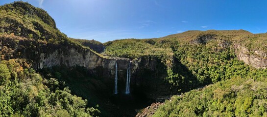 Aerial view of waterfall cascading off a cliff into lush valley