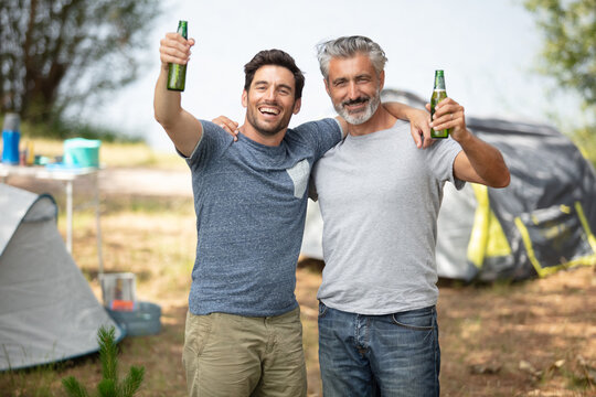 happy men drinking beer at campsite tent - Powered by Adobe