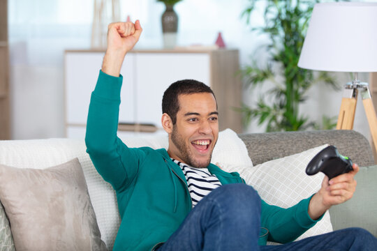 young man celebratig a computer game victory - Powered by Adobe