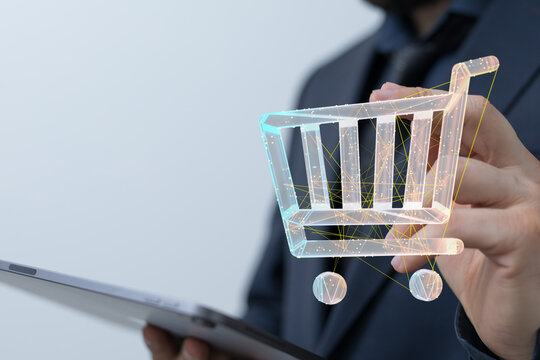 A businessperson holding a digital shopping cart icon with a tablet, symbolizing online retail and e-commerce transactions.