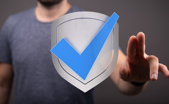 A person interacting with a digital shield icon representing safety, security, and approval in a virtual world concept. Ideal for cyb
