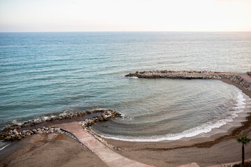 Serene coastal view with gentle waves and rocky shoreline at sunset