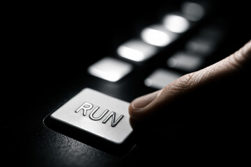 Minimalist close up a hand pressing a RUN button on a keyboard conveying action motion and trigger a process with high contrast and focus on the button