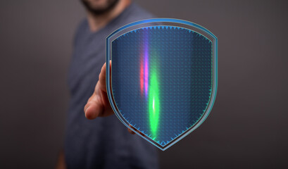 A man's hand reaching towards a glowing shield, a metaphor for security, privacy, and protection in...