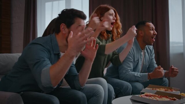 Excited football fans four multiethnic friends watching tv screaming happiness supporters spectators celebrating television win men women at home party emotional millennials in living room having fun