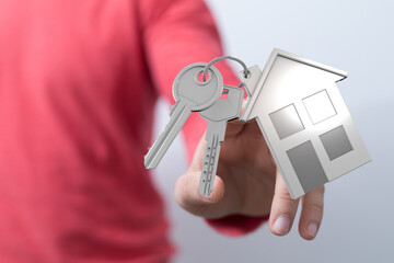Close-up shot of a hand holding a house key and house symbol, symbolizing homeownership, real...