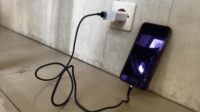 Smartphone Charging on Wall Socket with Cable Plugged In. Concept of battery charging, electricity usage, mobile technology, and daily digital lifestyle. Suitable for technology and communication.