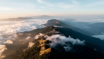 Serene aerial view captures majestic mountain peaks rising above a soft blanket of swirling clouds during the golden hour, presenting a breathtaking natural landscape with layered silhouettes