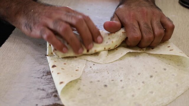 Filling lavash with sizzling fried meat for street food wrap