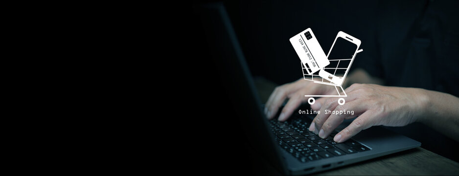 Person using laptop with virtual shopping cart icon containing smartphone and credit card, representing online shopping, e-commerce, internet transactions, and digital payment technology. - Powered by Adobe