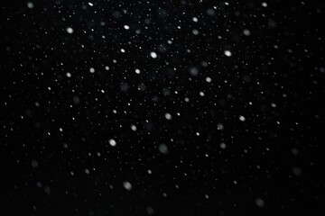Falling snow particles in a dark winter night, atmospheric snowfall effect, winter precipitation