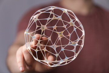 Close-up of a hand holding a glowing 3D-printed sphere representing a digital network or futuristic concept. The image symbolizes com