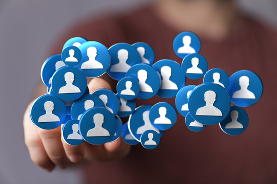 Hand holding a cluster of blue person icons representing network, community and connection. Digital concept for social media, teamwork and commu - Powered by Adobe