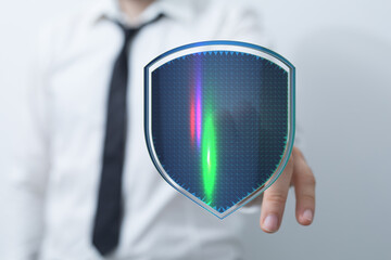 A businessperson holds a digital shield representing security, data protection and cyber security concepts. Represents secure online