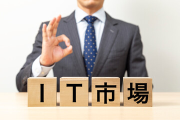 「IT市場」と書かれたブロックとOKポーズをするビジネスマン