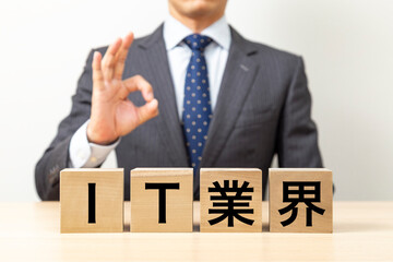 「IT業界」と書かれたブロックとOKポーズをするビジネスマン