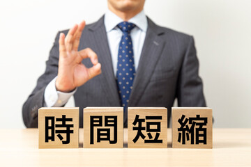 「時間短縮」と書かれたブロックとOKポーズをするビジネスマン