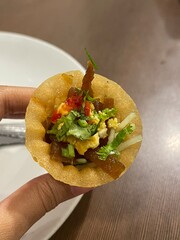 Close-up shot of a hand holding a Malaysian pie tee filled with vegetables. Traditional local...