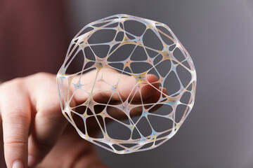 Abstract design of a sphere made of lines held in hand. Concept of interconnectedness, network, technology, data, and future. Artisti
