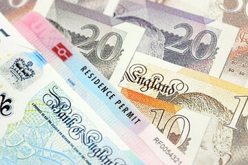 United Kingdom BRP Residence Permit card on many UK British pounds money close up