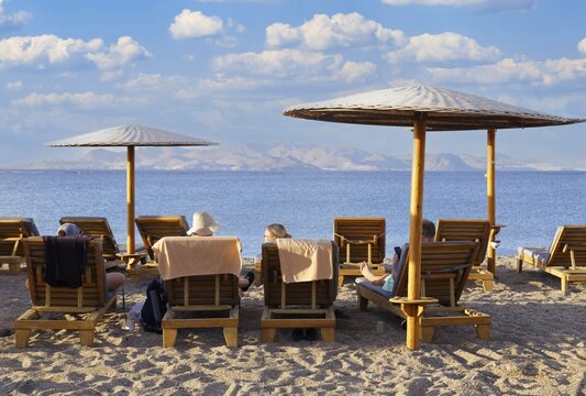 Parasol, sun lounger, sea, pebble beach, piled up with sand, people on the beach, behind Turkish coast, Hotel Mitsis Ramira, Psalidi region, island of Kos, Dodecanese Islands, Greece