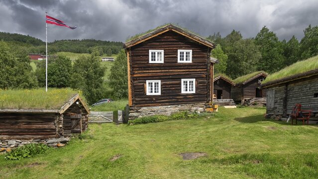 Norwegische Holzhäuser mit Gras auf den Dächern, Fahnenmast mit Norwegen-Flagge, historischer Bauernhof und Pilgerunterkunft Budsjord, Dovre, Pilgerweg Olavsweg oder Olavsleden, Gudbrandsdalen oder Gudbrandstal, Norwegen