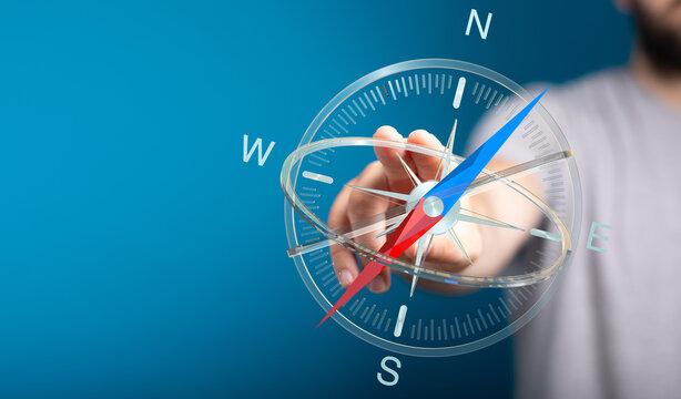 A hand touching a compass represents direction, guidance, and travel. Ideal for navigation, exploration, and goal setting concepts.