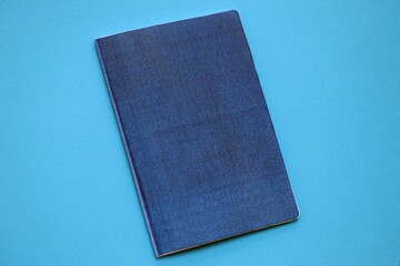 Generic passport book on light blue paper background close up. Travel document on blue surface
