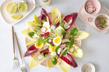 Salat mit Chicoree, Radicchio, Radieschen, gekochten Eiern und Limettendressing