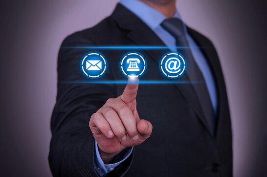Businessman pointing to glowing icons for email, telephone, and email contact options - Powered by Adobe